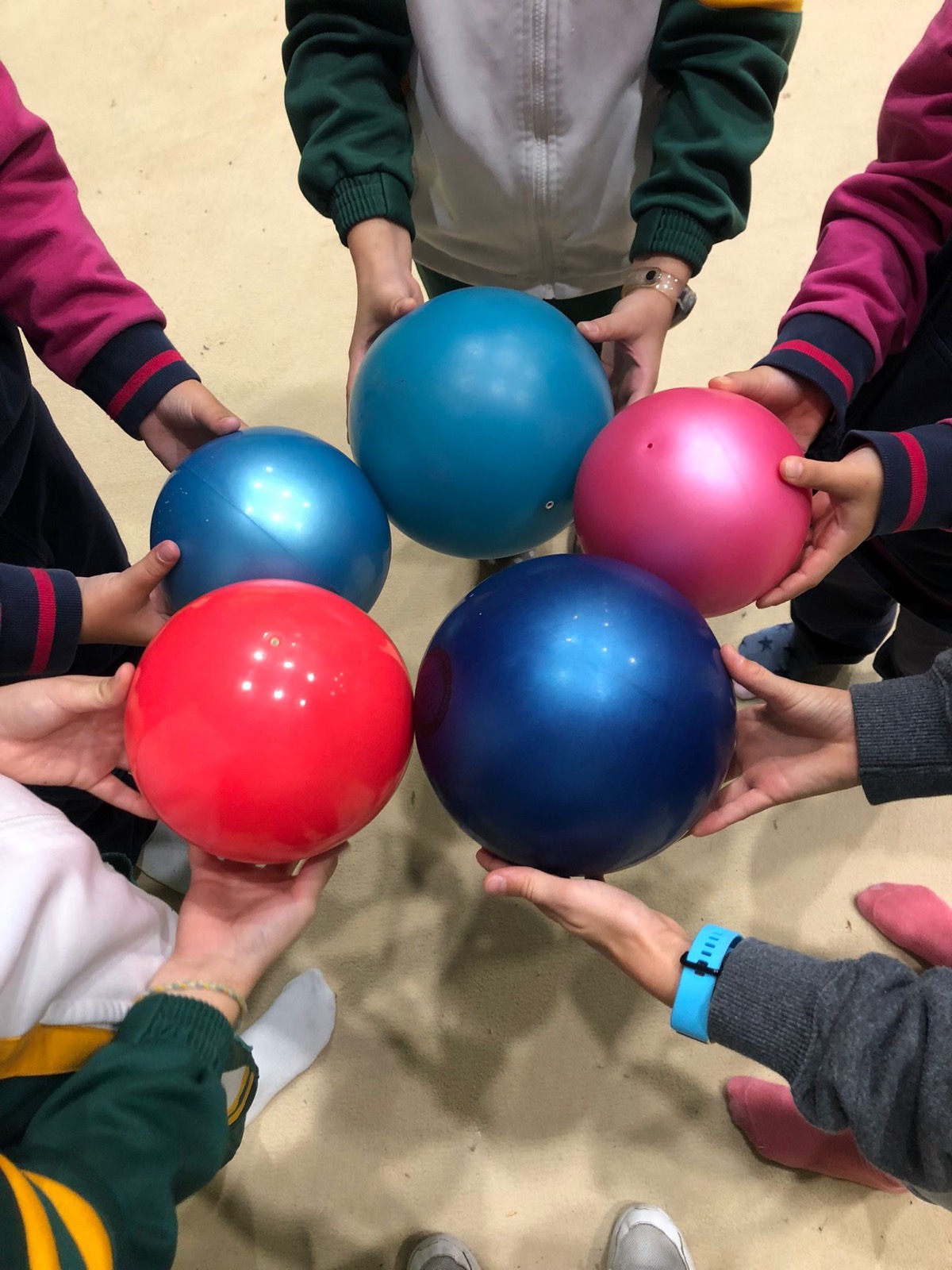 Manos de las gimnastas de escuela sujetando sus pelotas en círculo