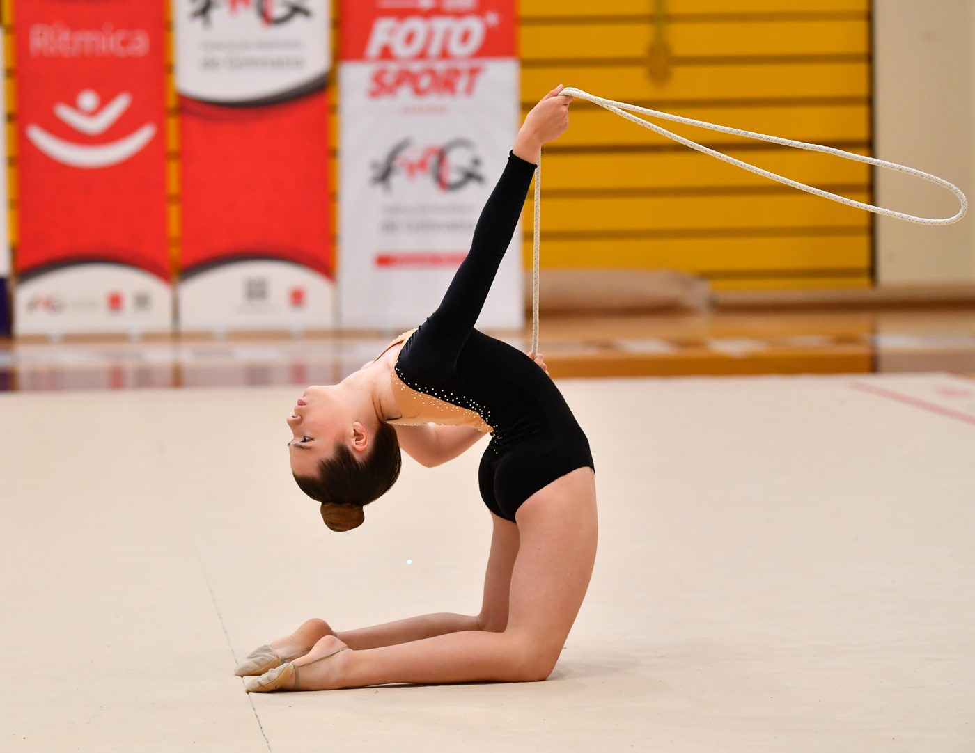 Gimnasta del club en un puente de rodillas con la cuerda