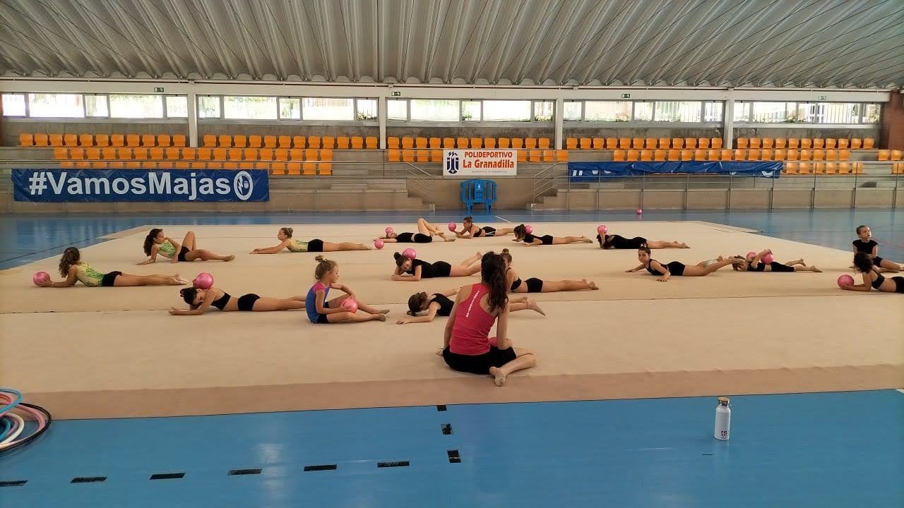 Las gimnastas estirando sobre el tapiz durante los entrenamientos de verano